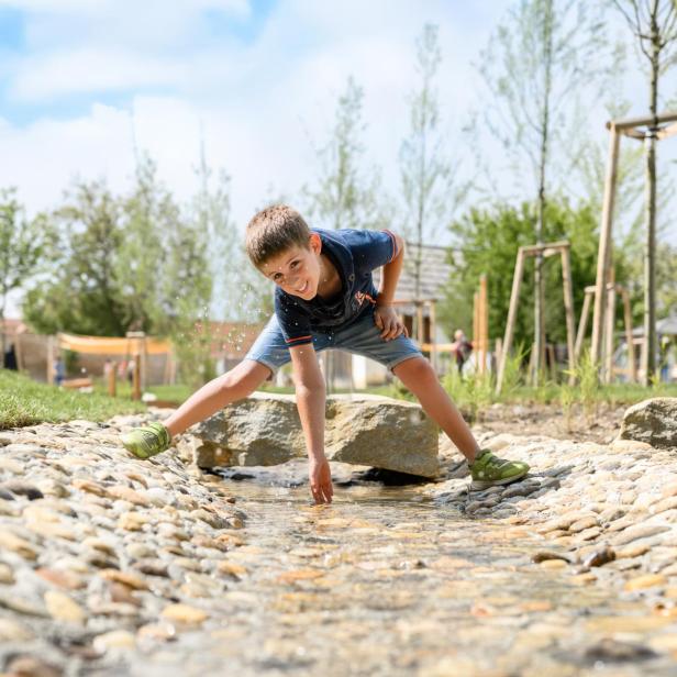 Ein Junge spielt in einem Wasserlauf. 