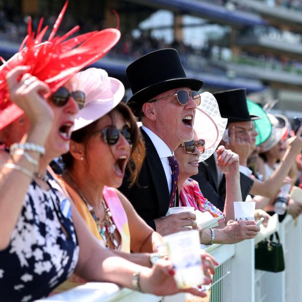 Besucher in Hüten und Anzügen jubeln auf der Pferderennbahn Royal Ascot.