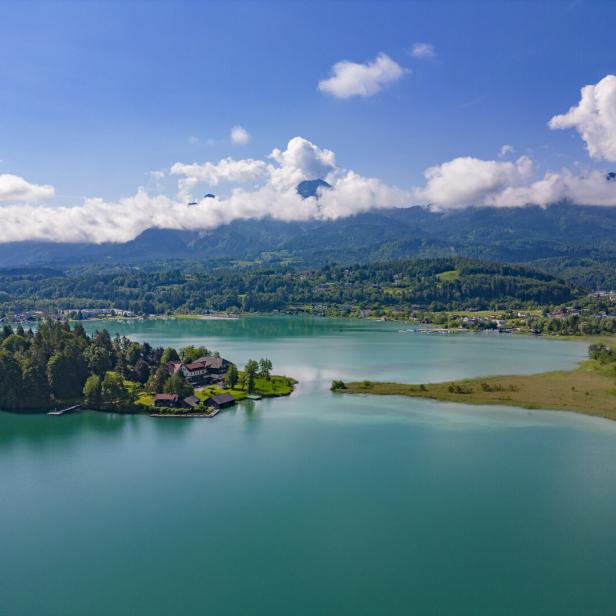 Blick auf den Faaker See mit Insel in der Mitte. Dahinter die Karawanken und der Mittagskogel.