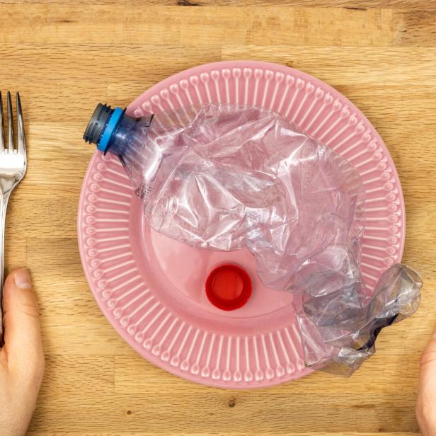 Microplastic in food, Concept, Global environmental problem, Plastic Pet bottle on a plate, hands reaching for a knife and fork, microplastics and pollution entering the body