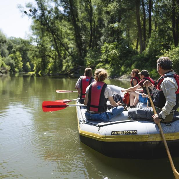 Eine Gruppe von Menschen fährt mit einem Schlauchboot auf einem Fluss entlang.