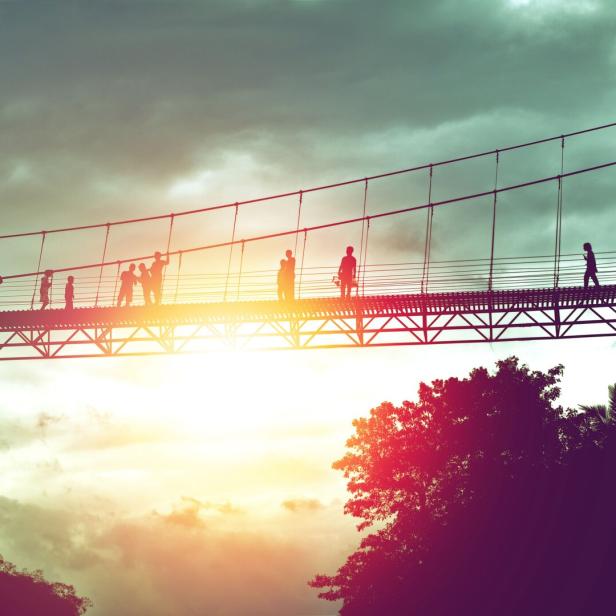 silhouette of tourist on suspension bridge walkway to the jungle in Surat Thani provine Thailand.