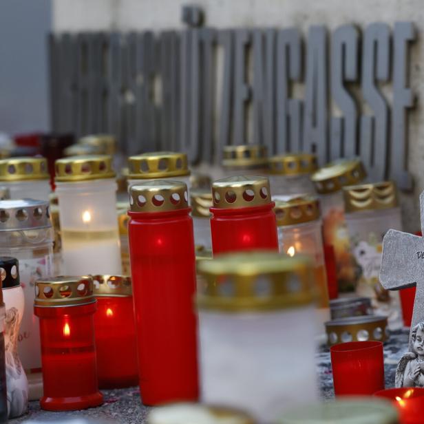 Kerzen und ein Kreuz mit der Aufschrift „Wir vermissen Dich“ vor einem Schulgebäude.
