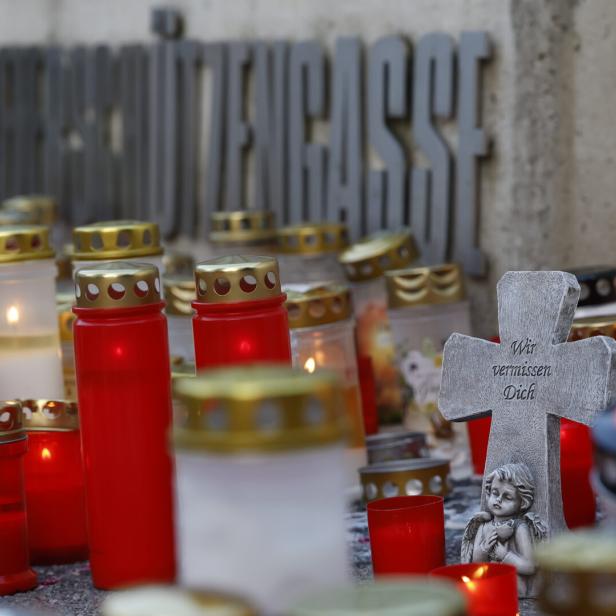 Kerzen und ein Kreuz mit der Aufschrift „Wir vermissen Dich“ vor einem Schulgebäude.
