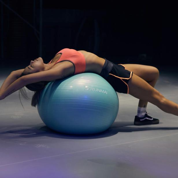 Eine Frau dehnt sich auf einem Gymnastikball. 