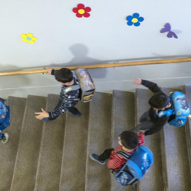Eine Gruppe von Schulkindern mit Rucksäcken steigt eine Treppe hinauf.
