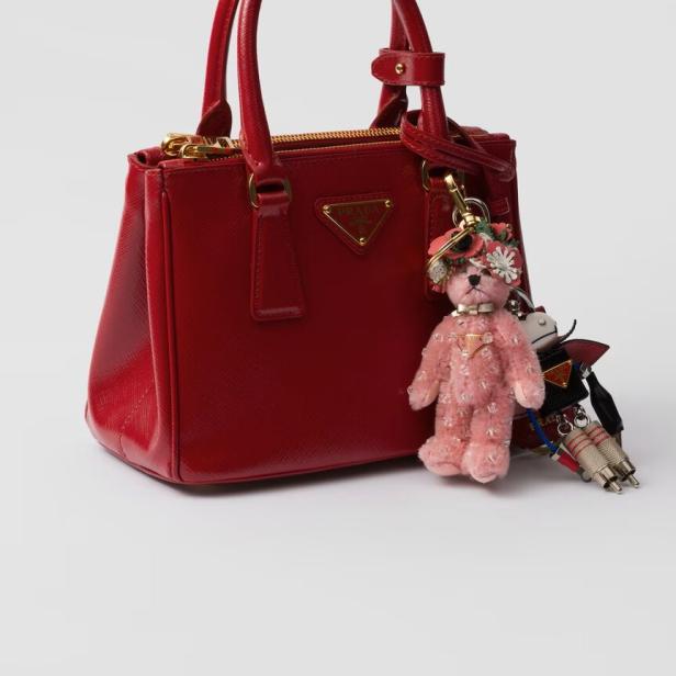 Eine rote Prada-Handtasche mit einem Teddybär- und einem Roboter-Schlüsselanhänger.