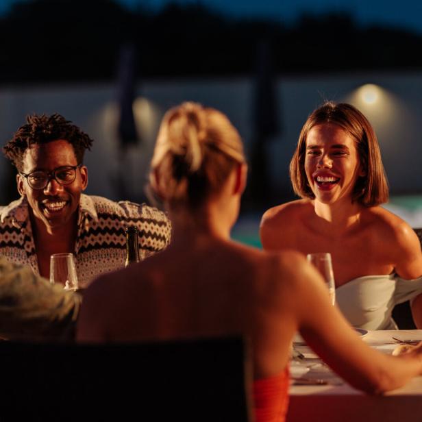 Freunde genießen ein gemeinsames Abendessen in einem luxuriösen Resort.