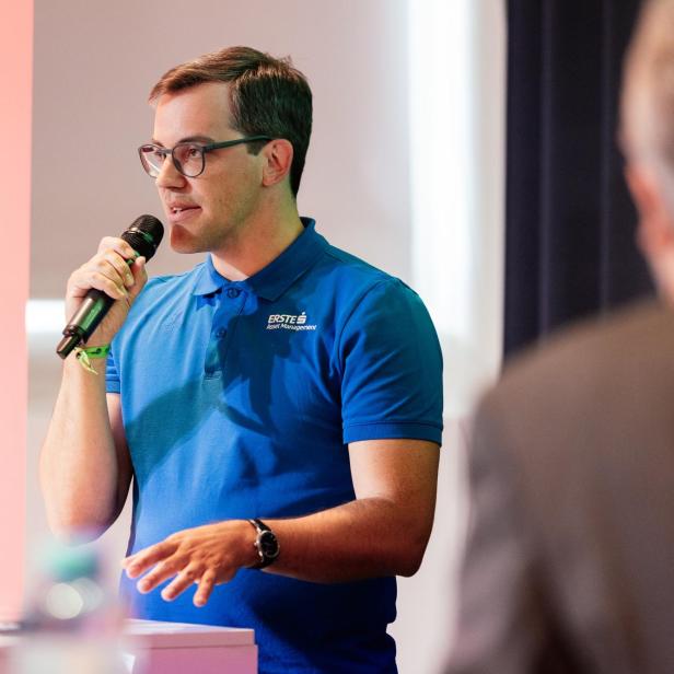 Ein Mann in einem blauen T-Shirt hält einen Vortrag. 