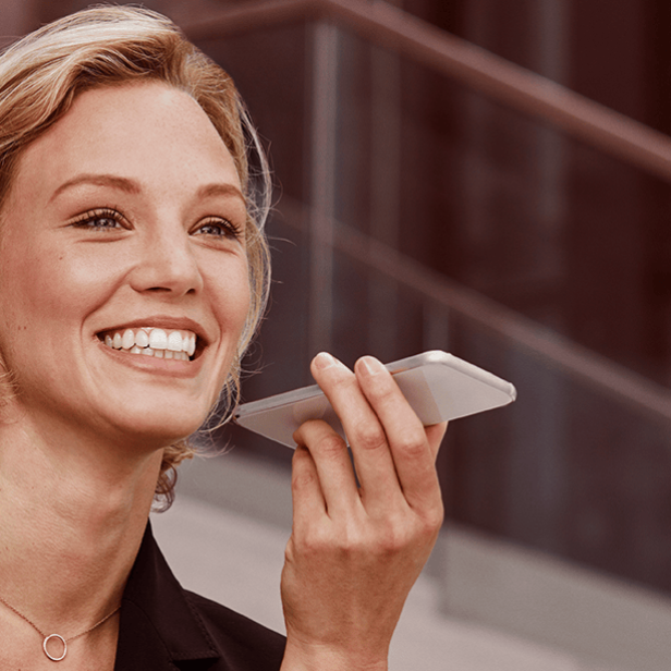 Eine Frau im Businessanzug hält ein Handy in der Hand.