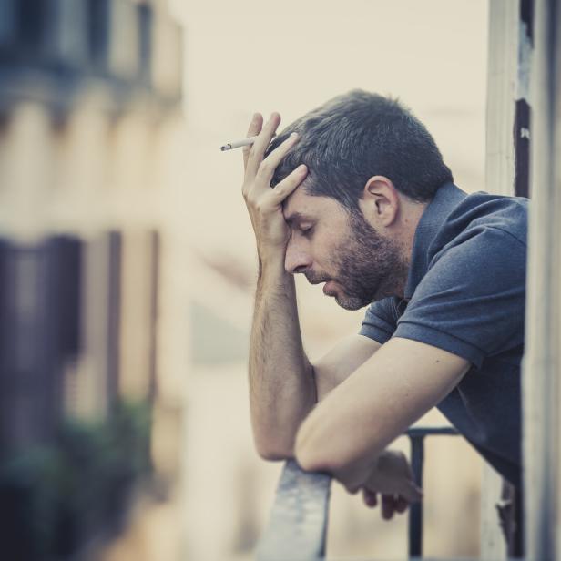 young man at balcony in depression suffering emotional crisis