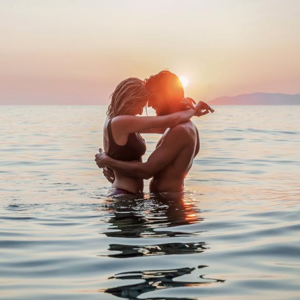 Ein Paar umarmt sich im Wasser bei Sonnenuntergang.