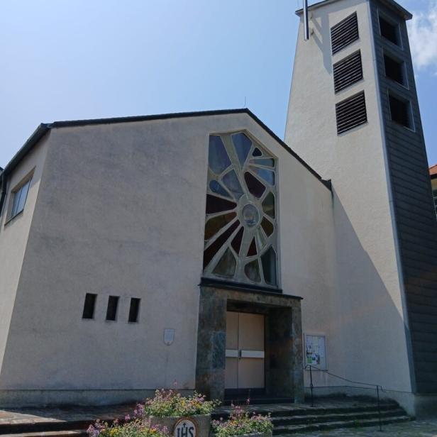 Eine moderne Kirche mit einem Turm und einem Kreuz unter blauem Himmel.