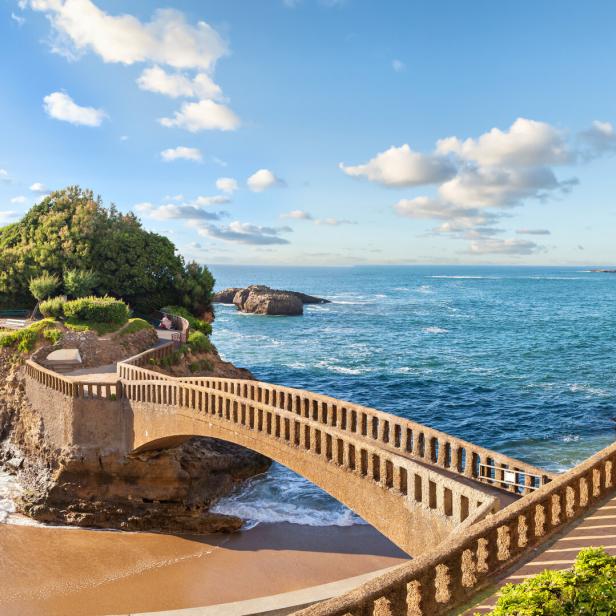 Eine Brücke führt zu einer kleinen, bewaldeten Insel in Biarritz.