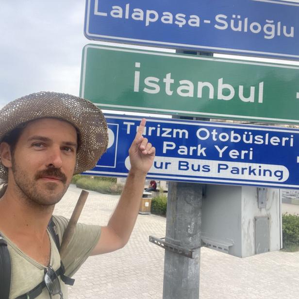 Ein Mann mit Hut steht vor Wegweisern nach Istanbul und Lalapaşa-Süloğlu.