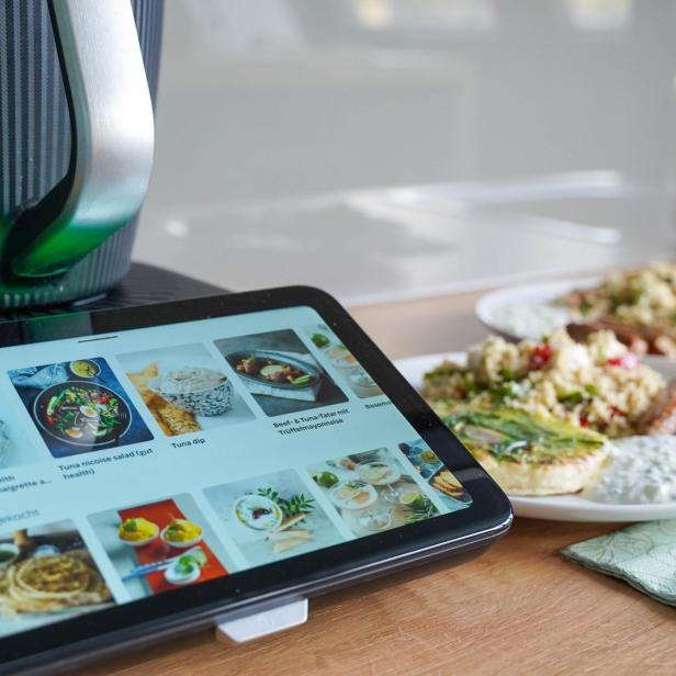 Der neue Thermomix 7 steht in der Küche auf der Arbeitsfläche und daneben steht ein Teller mit fertig zubereiteten Speisen angerichtet.