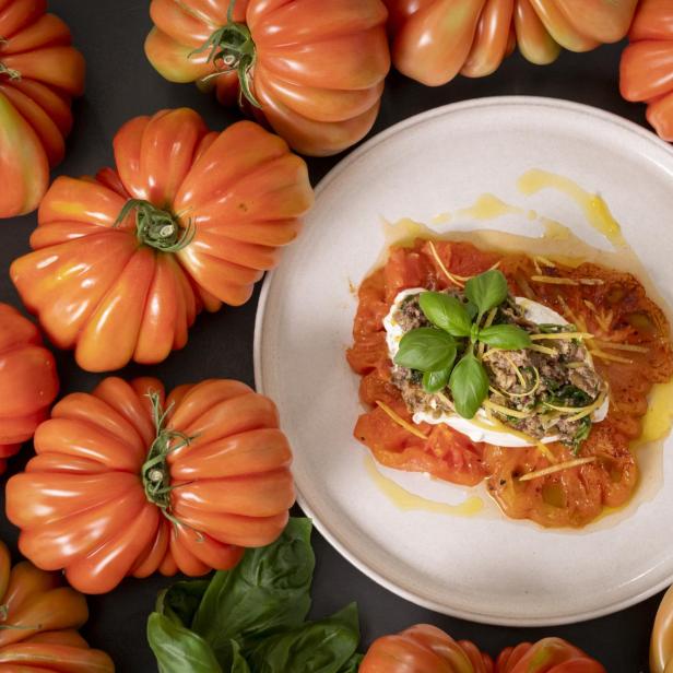 Ein Teller mit frischen Tomaten, darauf eine Scheibe Käse.