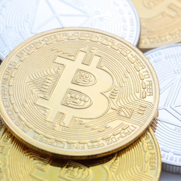 Mehrere goldene und silberne Bitcoin- und Ethereum-Münzen liegen übereinander.