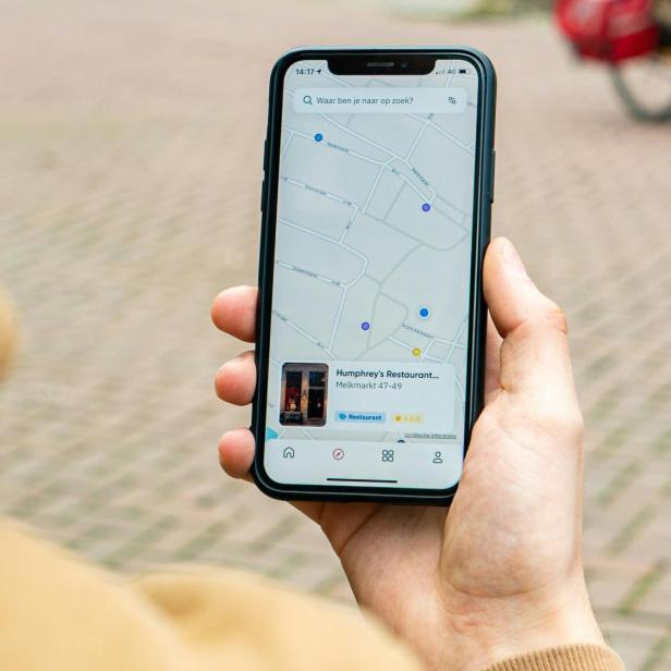 Person hält Handy in der Hand und schaut auf Google Maps Karte