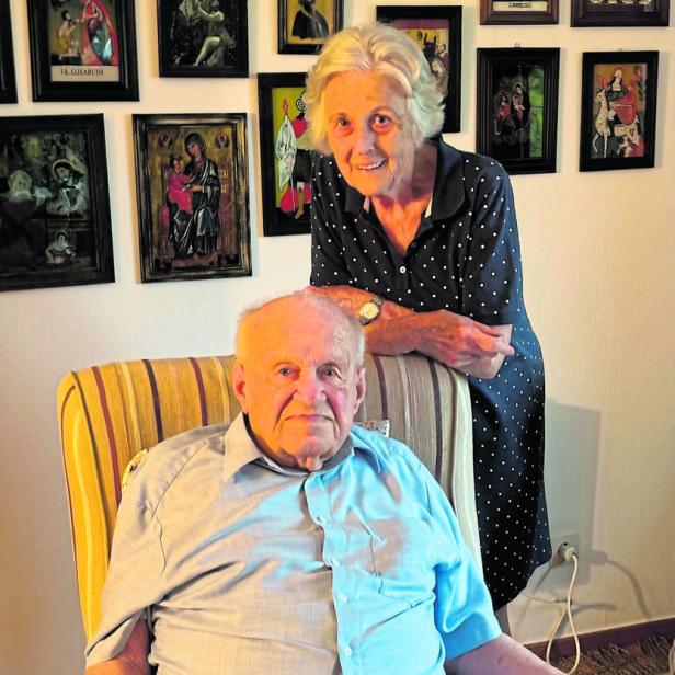 Anneliese Ratzenböck mit einem älteren Mann vor einer Wand mit Bildern.