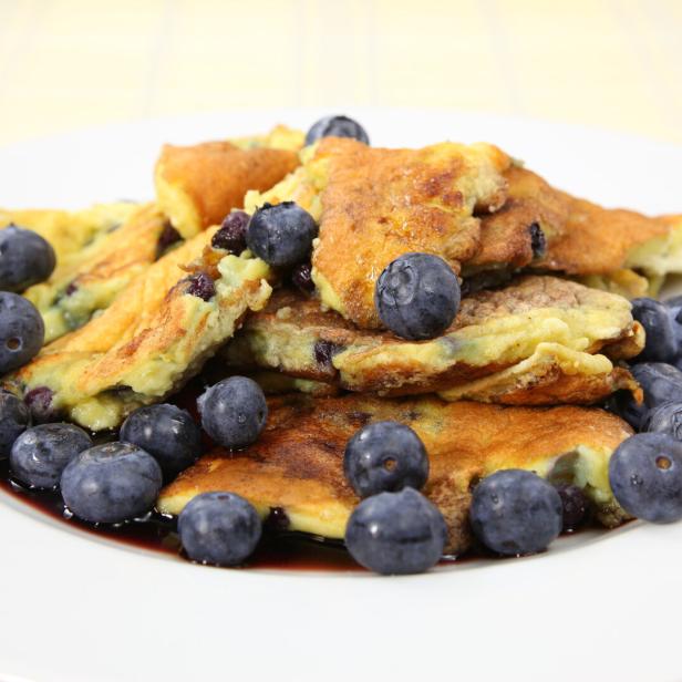Ein Teller mit flaumigem Kaiserschmarrn, garniert mit frischen Blaubeeren.