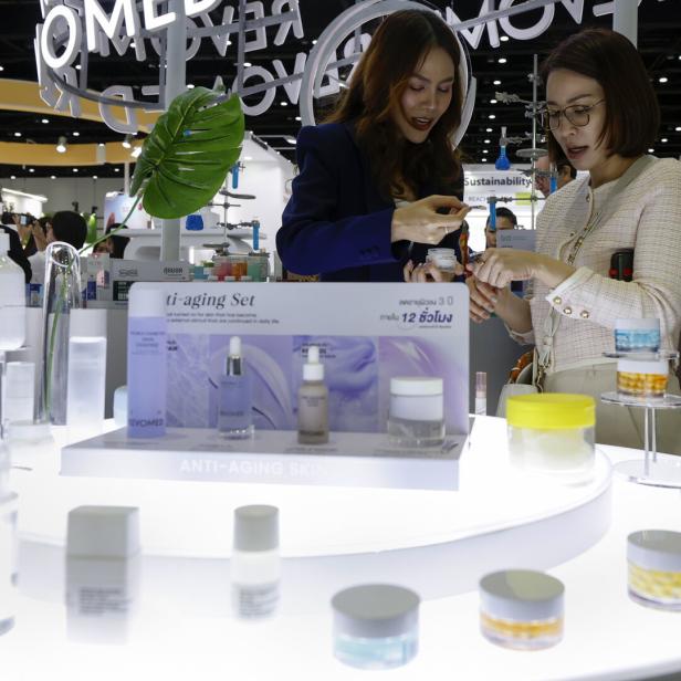 Zwei Frauen betrachten auf der Cosmoprof CBE ASEAN in Bangkok Anti-Aging-Produkte.