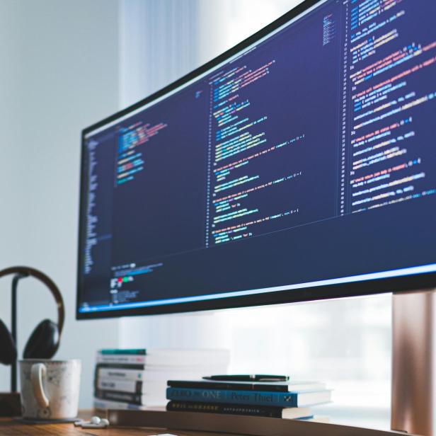 Ein Schreibtisch mit einem Computerbildschirm, der Codes anzeigt.