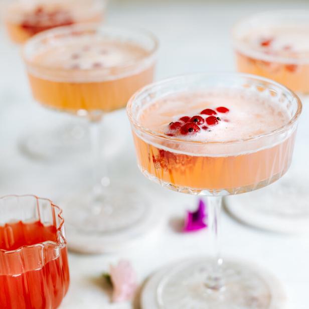 Mehrere Gläser mit einem rosa Getränk und roten Johannisbeeren stehen auf einem Tisch.