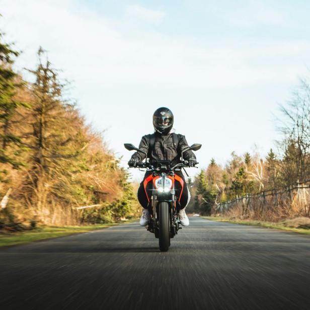Ein Motorradfahrer fährt auf einer Landstraße.