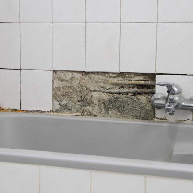 An old bathroom with broken white tiles and mold