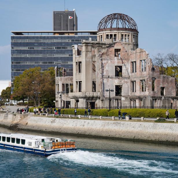 Ein Boot fährt auf dem Fluss vor der Ruine des Atombomben-Denkmals in Hiroshima.