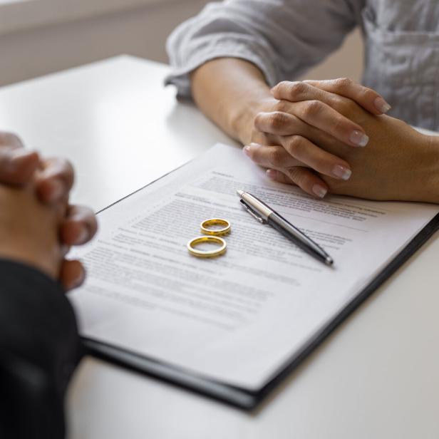 Partner sitzen gegenüber am Tisch liegt ein Vertrag.