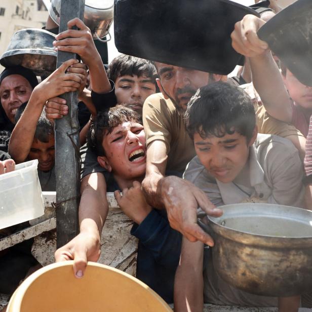 Palestinians wait to receive food from a charity kitchen, in Gaza City