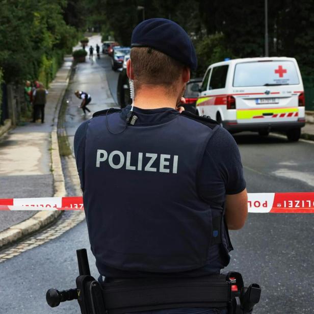 Ein Polizist steht vor einer Polizeiabsperrung auf einer Straße.