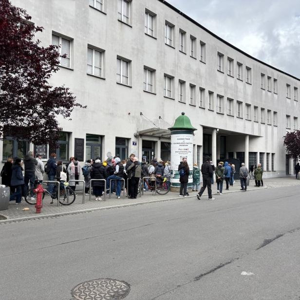 Vor der ehemaligen Emailwarenfabrik bilden sich lange Menschenschlangen.