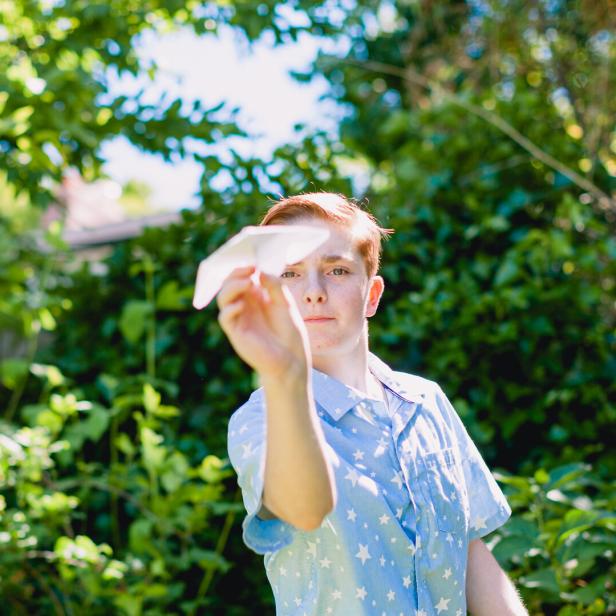 Teenage Boy Throwing Paper Airplane