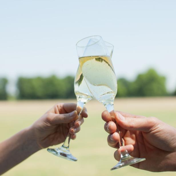 Ein Paar stößt mit Champagnergläsern im Freien an.