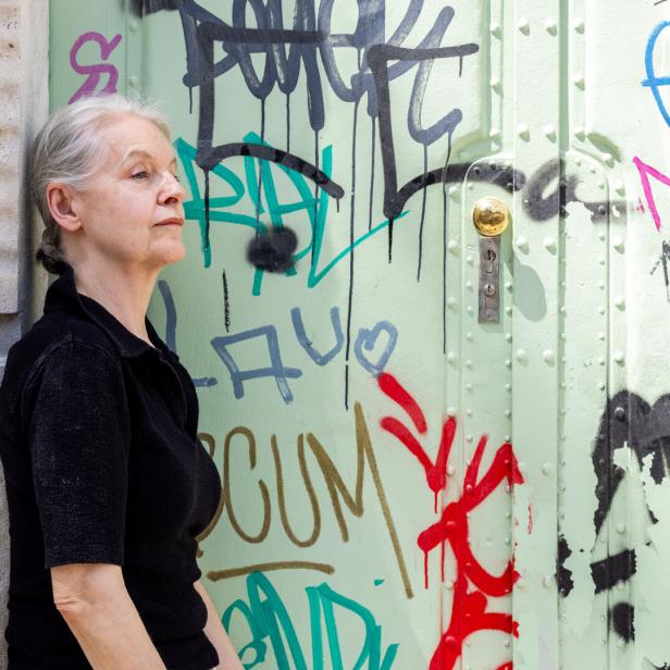 Marlene Streeruwitz steht vor einer mit Graffiti besprühten Tür.