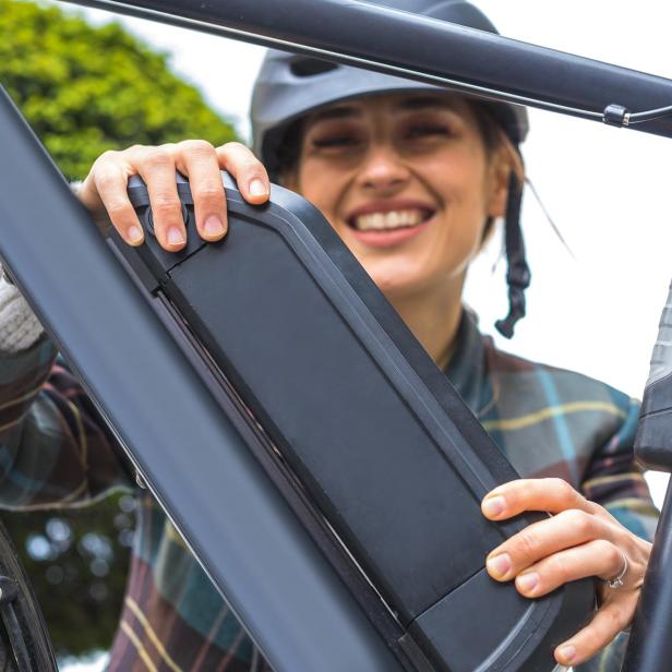 Eine Frau wechselt den Akku ihres E-Bikes aus.