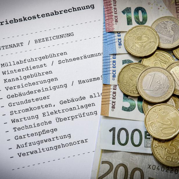 Eine Betriebskostenabrechnung liegt neben Euro-Banknoten und Münzen.