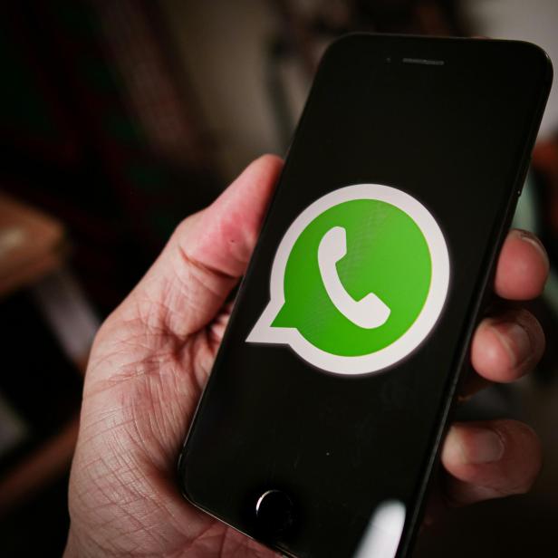 iPhone mit WhatsApp-Logo als Hintergrund