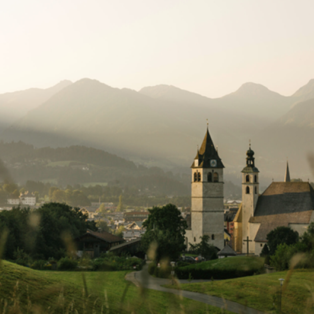 Eine Kirche in den Bergen, umgeben von majestätischen Gipfeln und üppigem Grün.