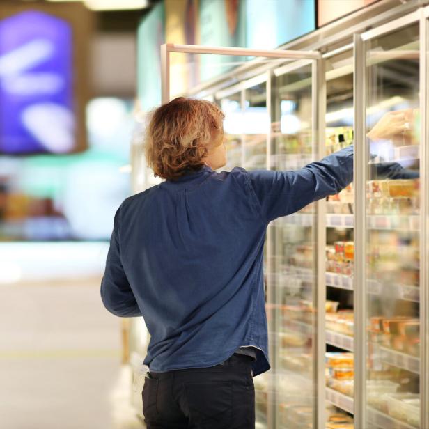 Man choosing frozen food from a supermarket freezer.
