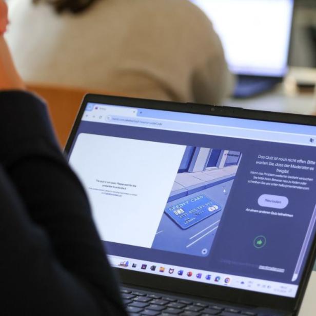 Ein Kind sitzt vor einem Laptop in einer Schulklasse.