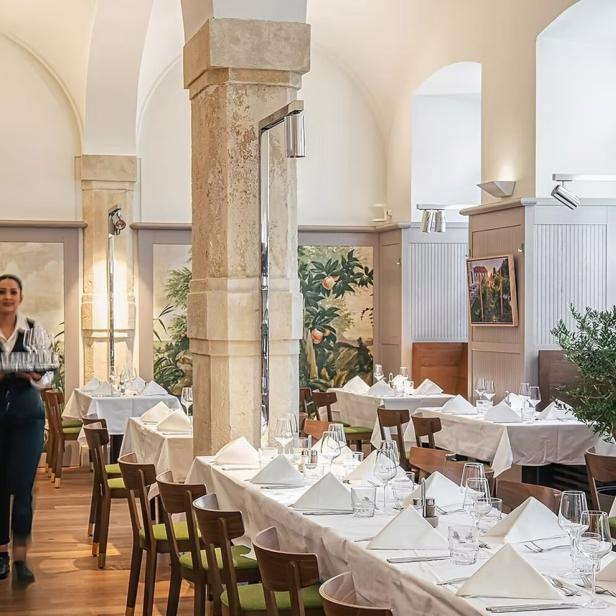 Eine Kellnerin trägt ein Tablett mit Gläsern in einem eleganten Restaurant.