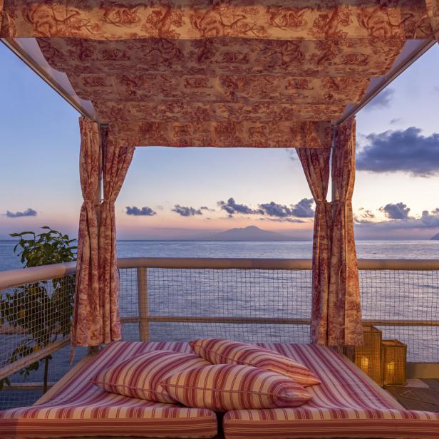 Ein Himmelbett mit Blick auf das Meer bei Sonnenuntergang.