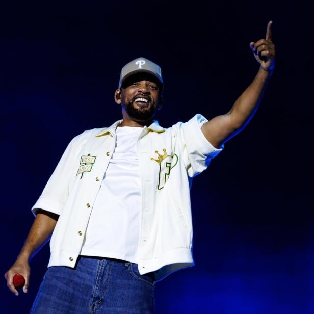 Will Smith steht auf einer Bühne und zeigt mit dem Finger nach oben.