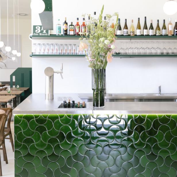 Eine Bar mit grünen Fliesen und Blumen in einer Vase.