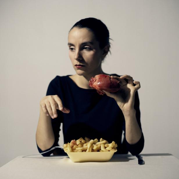 Die Künstlerin hinter einer großen Schale Pommes Frites - dazu hält sie ein (wohl künstliches) Herz in der Hand.