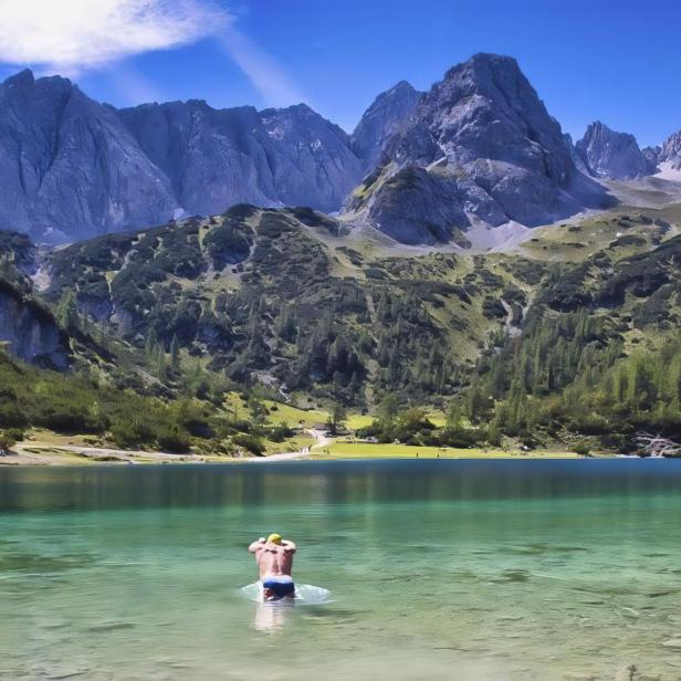 Ein Schwimmer im türkisfarbenen Wasser des Sebensees vor einer Bergkulisse.